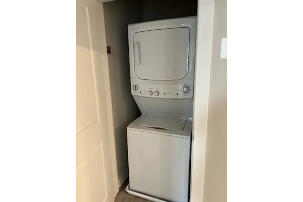 A white dishwasher is sitting in a narrow space between a door and a wall.